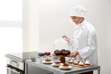 Photo of Female chef with pastries at table in kitchen