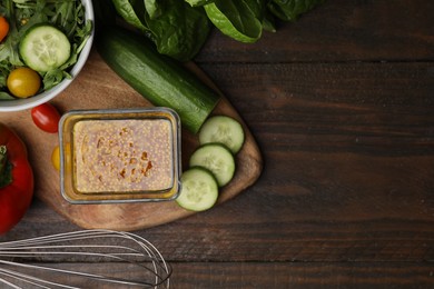 Tasty vinegar based sauce (Vinaigrette) in bowl, salad and products on wooden table, flat lay. Space for text