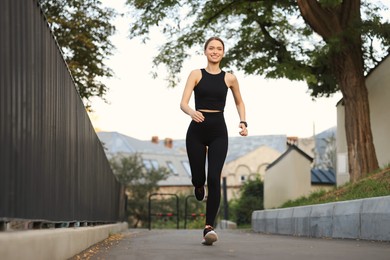 Photo of Attractive sporty woman in fitness clothes jogging outdoors