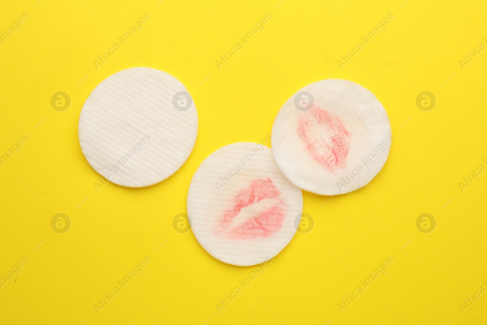 Photo of Clean and dirty cotton pads after removing makeup on yellow background, flat lay