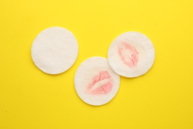 Photo of Clean and dirty cotton pads after removing makeup on yellow background, flat lay