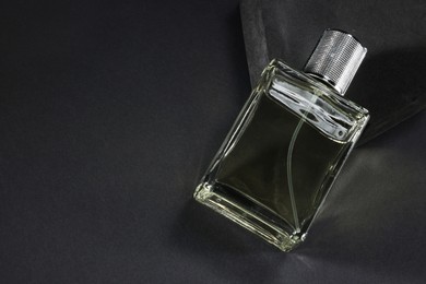 Photo of Stylish presentation of luxury men`s perfume in bottle on black background, above view. Space for text