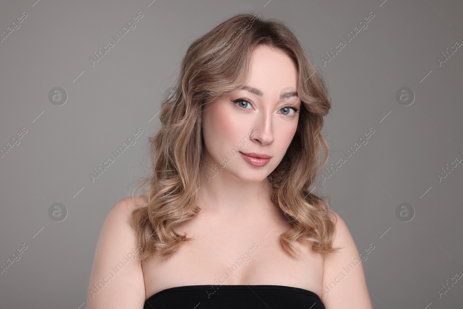 Photo of Portrait of beautiful woman with curly hair on grey background