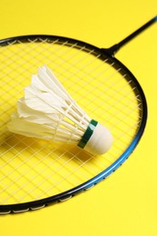 Photo of Feather badminton shuttlecock and racket on yellow background