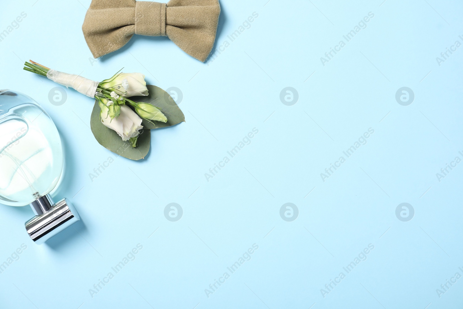 Photo of Wedding stuff. Stylish boutonniere, bow tie and perfume on light blue background, flat lay. Space for text