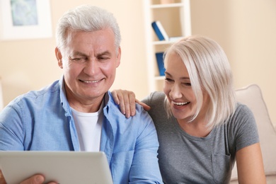 Mature couple using video chat on tablet at home