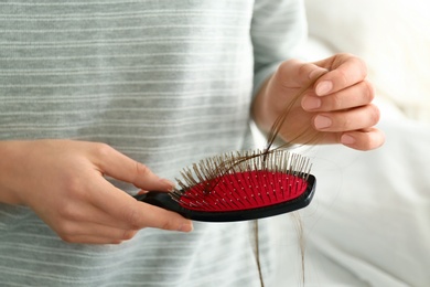 Photo of Woman holding brush with fallen long hair, closeup
