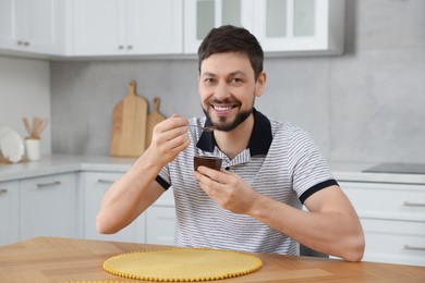 Photo of Handsome man with tasty yogurt at table in kitchen