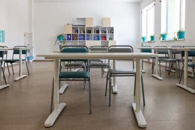 Empty school classroom with desks, windows and chairs