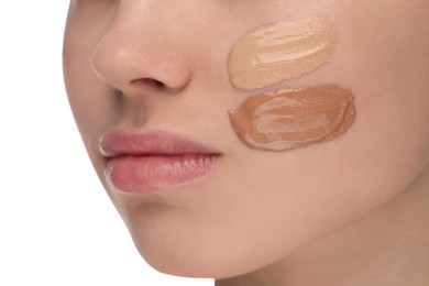 Teenage girl with swatches of foundation on face against white background, closeup
