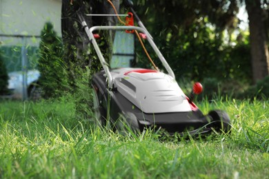 Image of Man cutting grass with lawn mower in garden, closeup