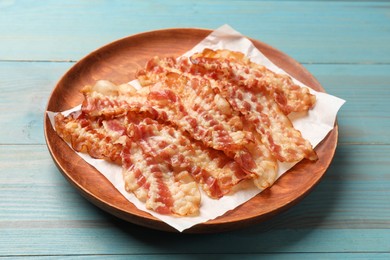 Photo of Delicious fried bacon slices on blue wooden table, closeup