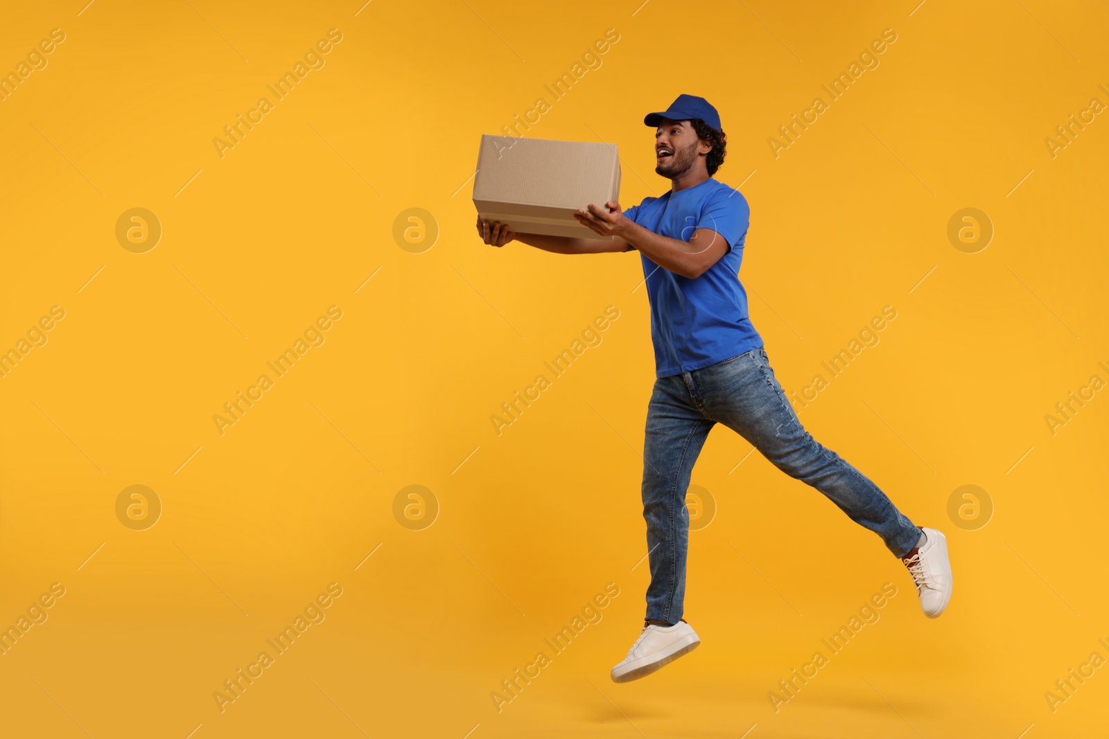 Photo of Happy courier running to deliver parcel on orange background, space for text