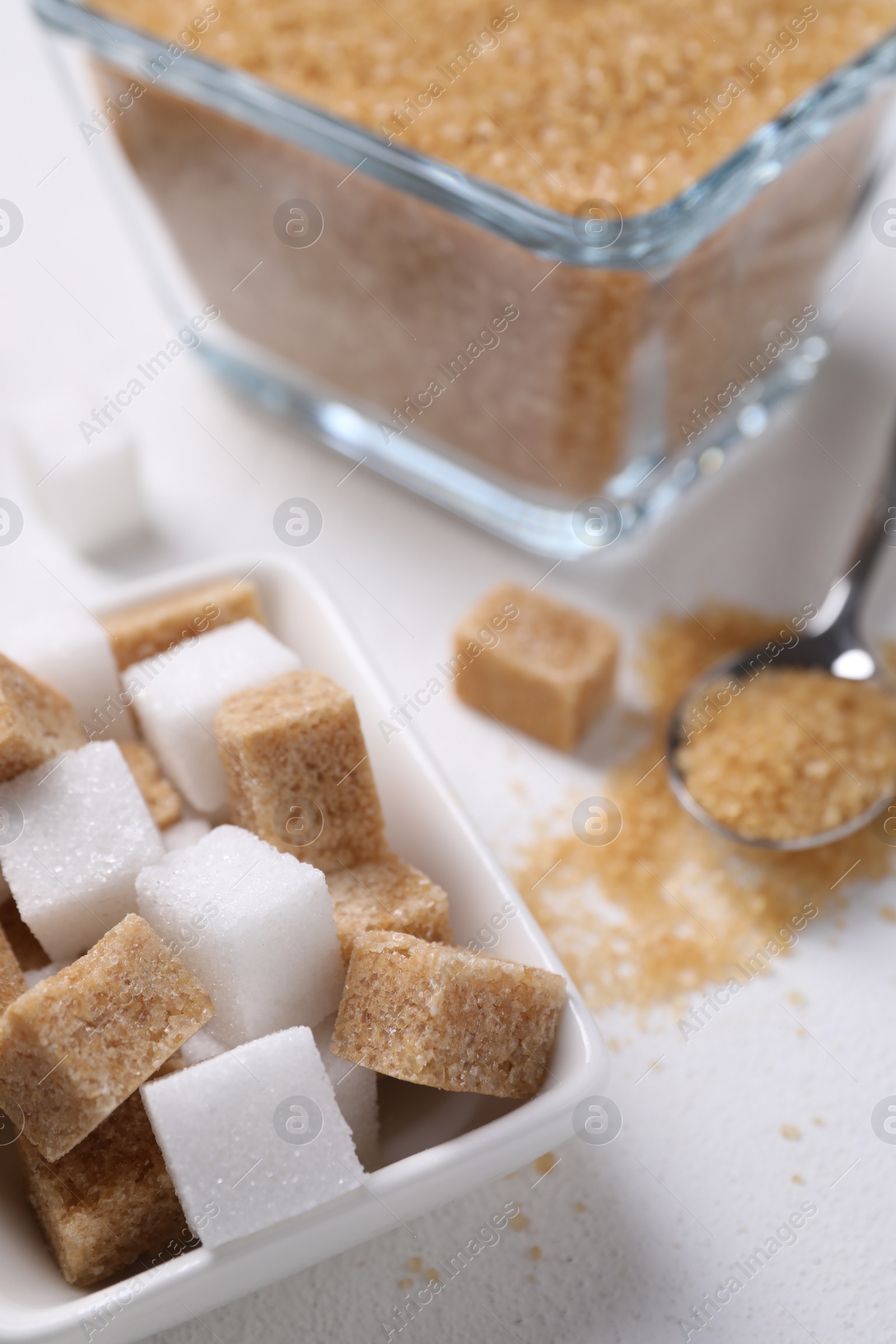 Photo of Different types of sugar in bowls on white table, closeup