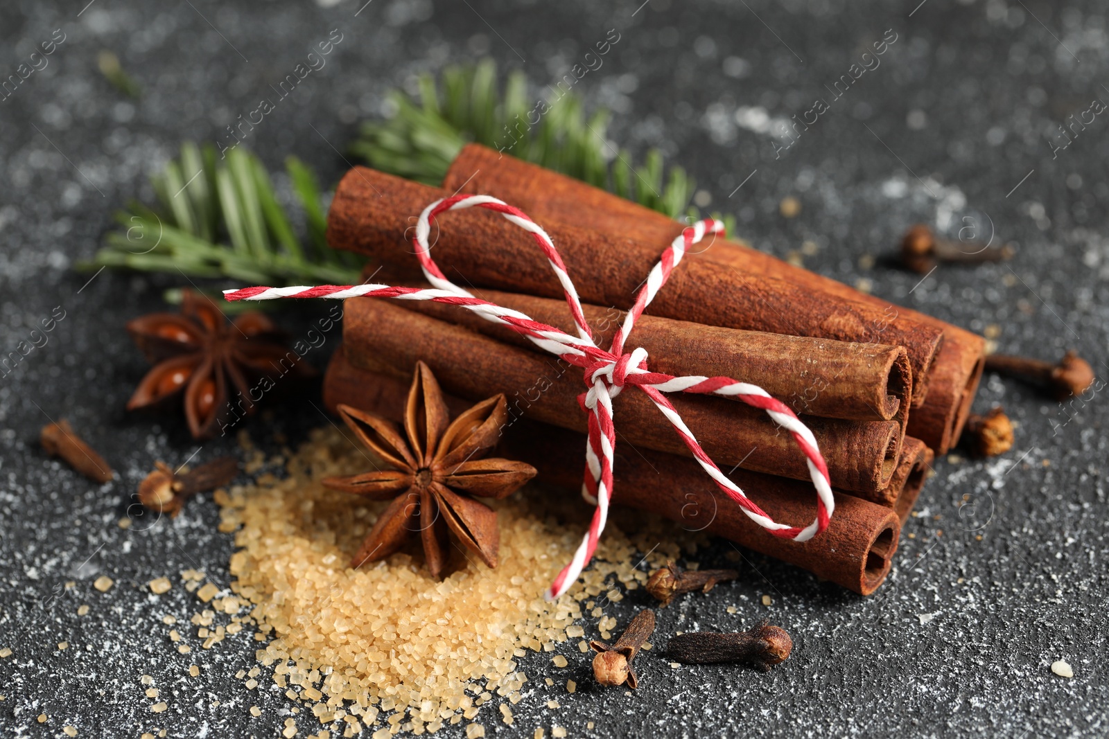 Photo of Different aromatic spices on grey textured table, closeup