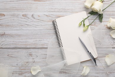 Photo of Guest list. Notebook, pen, rose flowers and ribbon on wooden background, flat lay. Space for text