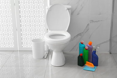 Photo of Toilet bowl and cleaning supplies in modern bathroom