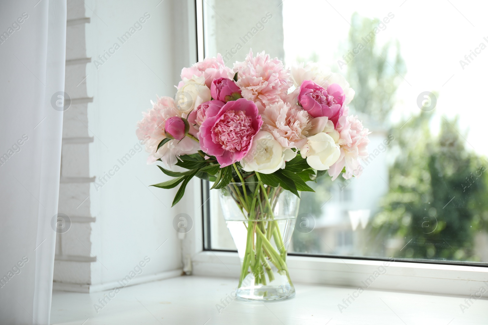 Photo of Beautiful peony bouquet in vase on windowsill indoors