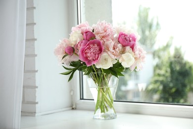 Photo of Beautiful peony bouquet in vase on windowsill indoors