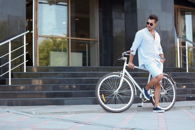 Photo of Handsome young hipster man with bicycle outdoors