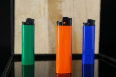 Photo of Stylish presentation of colorful plastic cigarette lighters standing on black and beige shelf