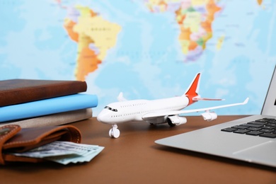 Composition with toy plane and laptop on table against map. Travel agency