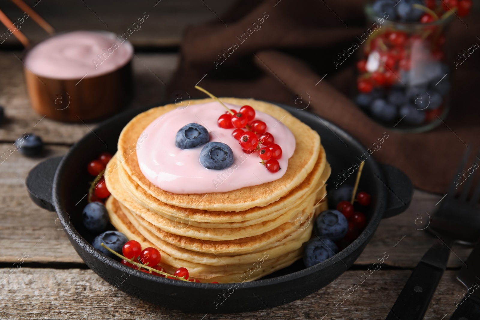 Photo of Tasty pancakes with natural yogurt, blueberries and red currants on wooden table