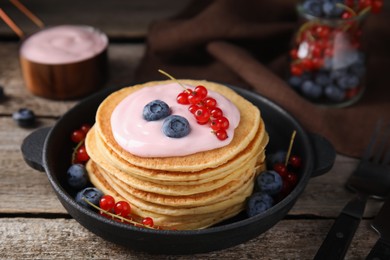 Photo of Tasty pancakes with natural yogurt, blueberries and red currants on wooden table