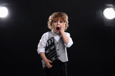 Emotional boy with clapperboard on stage. Little actor