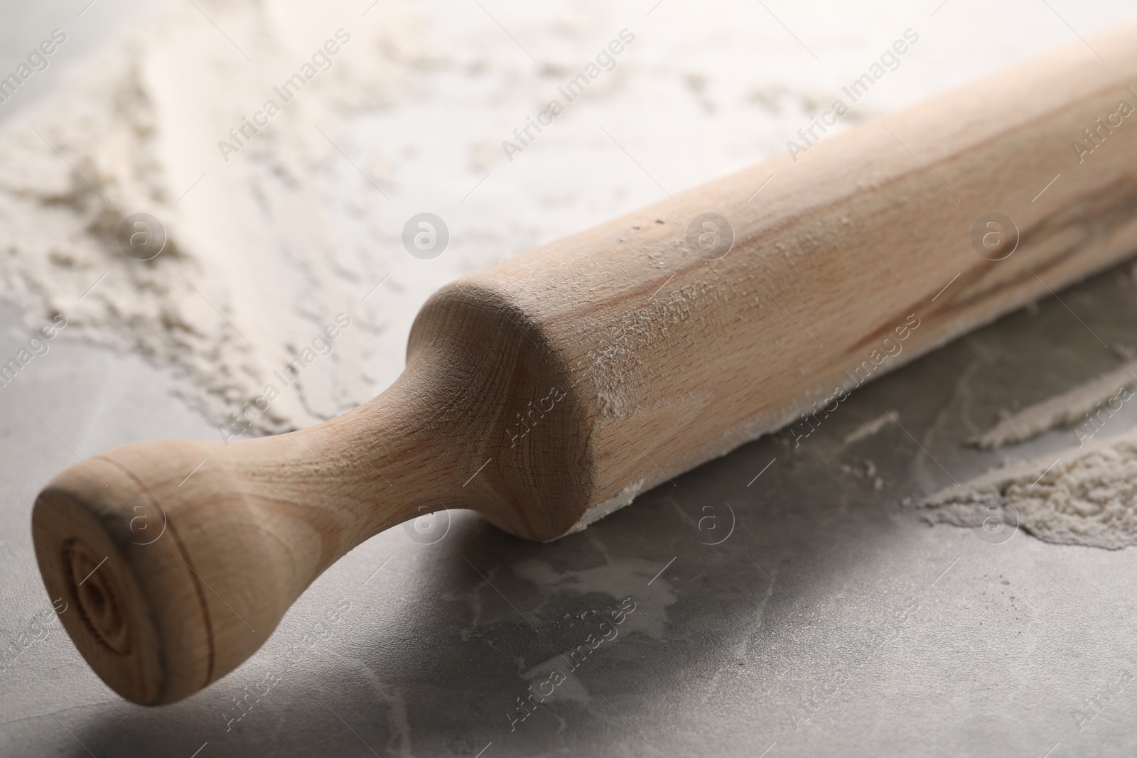 Photo of Rolling pin and flour on grey marble table, closeup