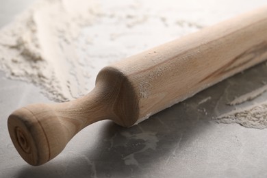 Photo of Rolling pin and flour on grey marble table, closeup