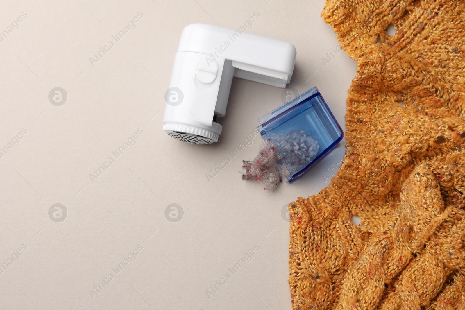 Photo of Modern fabric shaver with fuzz and knitted sweater on white background, flat lay. Space for text