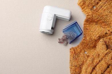 Modern fabric shaver with fuzz and knitted sweater on white background, flat lay. Space for text