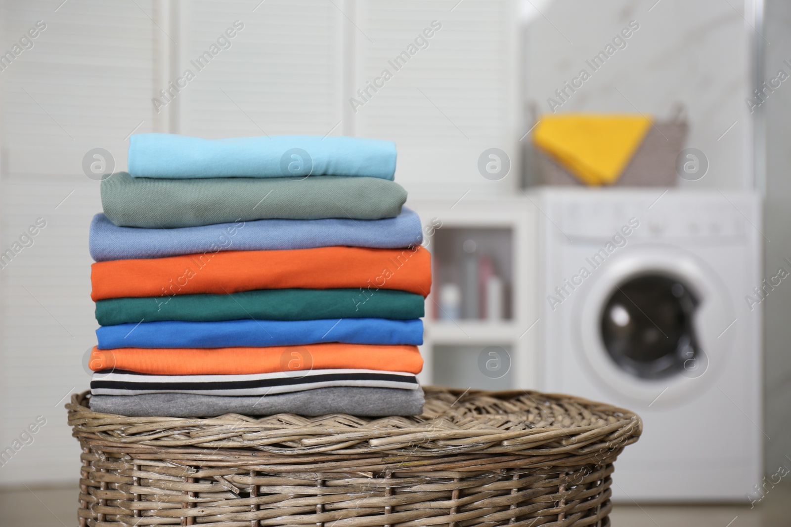 Photo of Stack of fresh laundry on basket in bathroom. Space for text