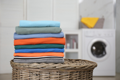 Stack of fresh laundry on basket in bathroom. Space for text