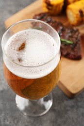 Photo of Glass of tasty beer on grey table, closeup