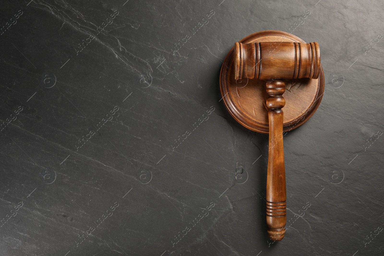 Photo of Wooden gavel on dark textured table, top view. Space for text