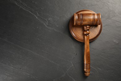 Photo of Wooden gavel on dark textured table, top view. Space for text