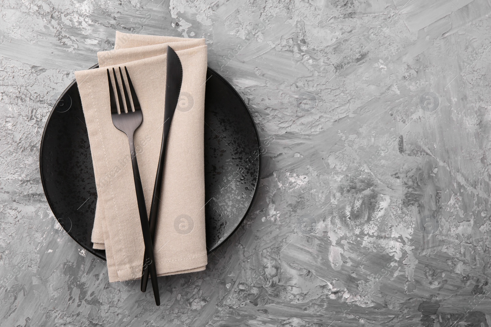 Photo of Elegant setting with stylish cutlery on grey textured table, top view. Space for text