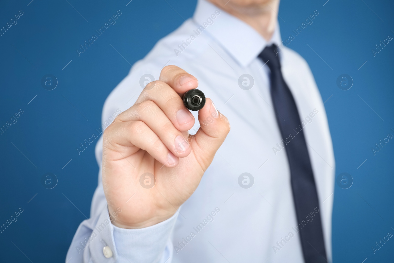 Photo of Businessman with marker against blue background, focus on hand