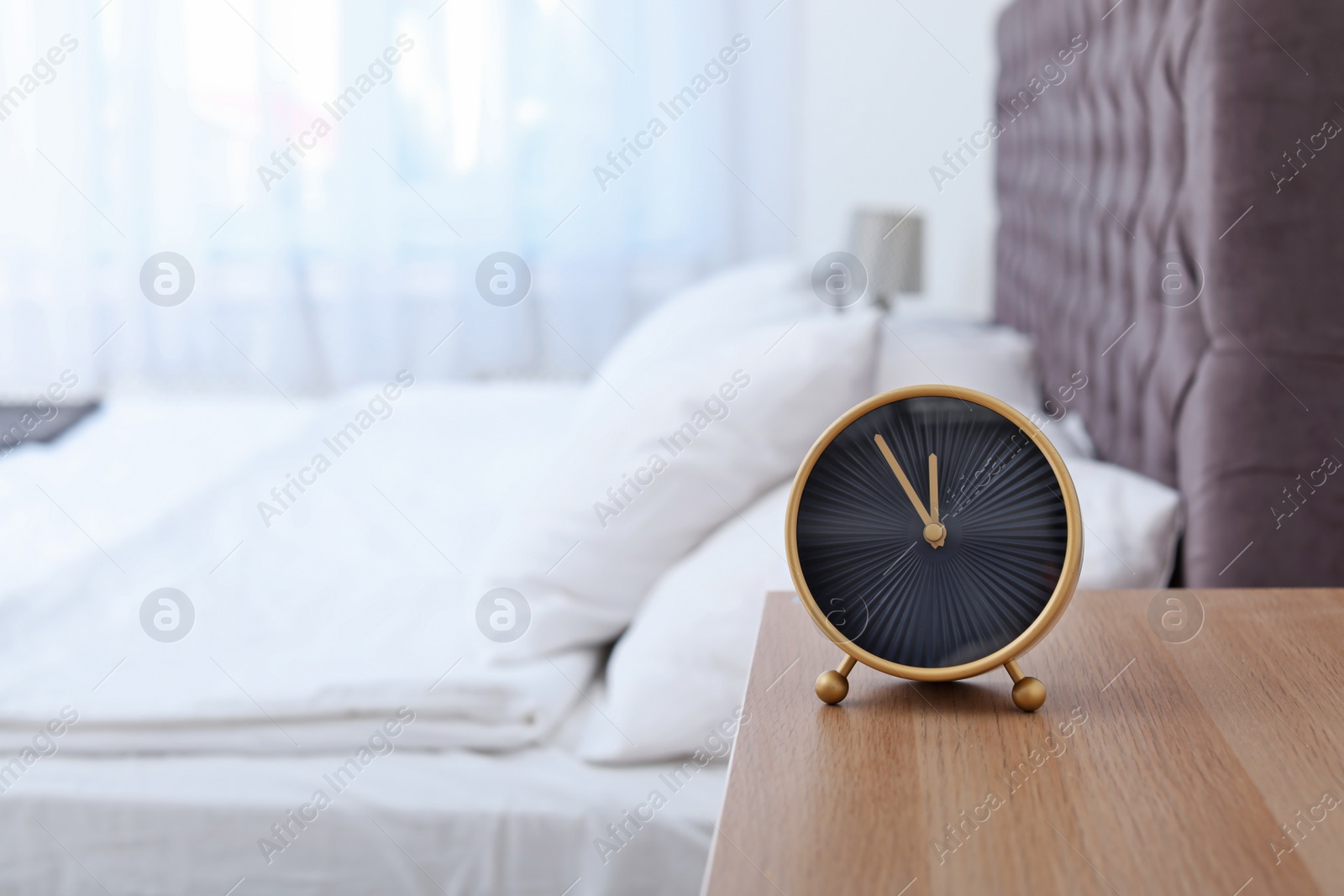 Photo of Stylish alarm clock on bedside table. Time to wake up