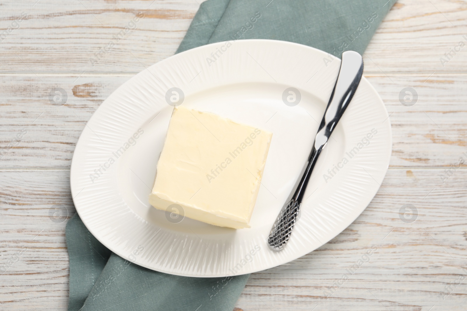 Photo of Block of tasty butter and knife on white wooden table