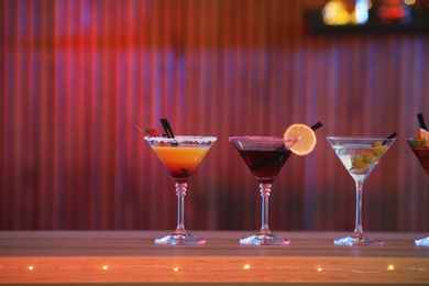 Different martini cocktails on table in bar, space for text