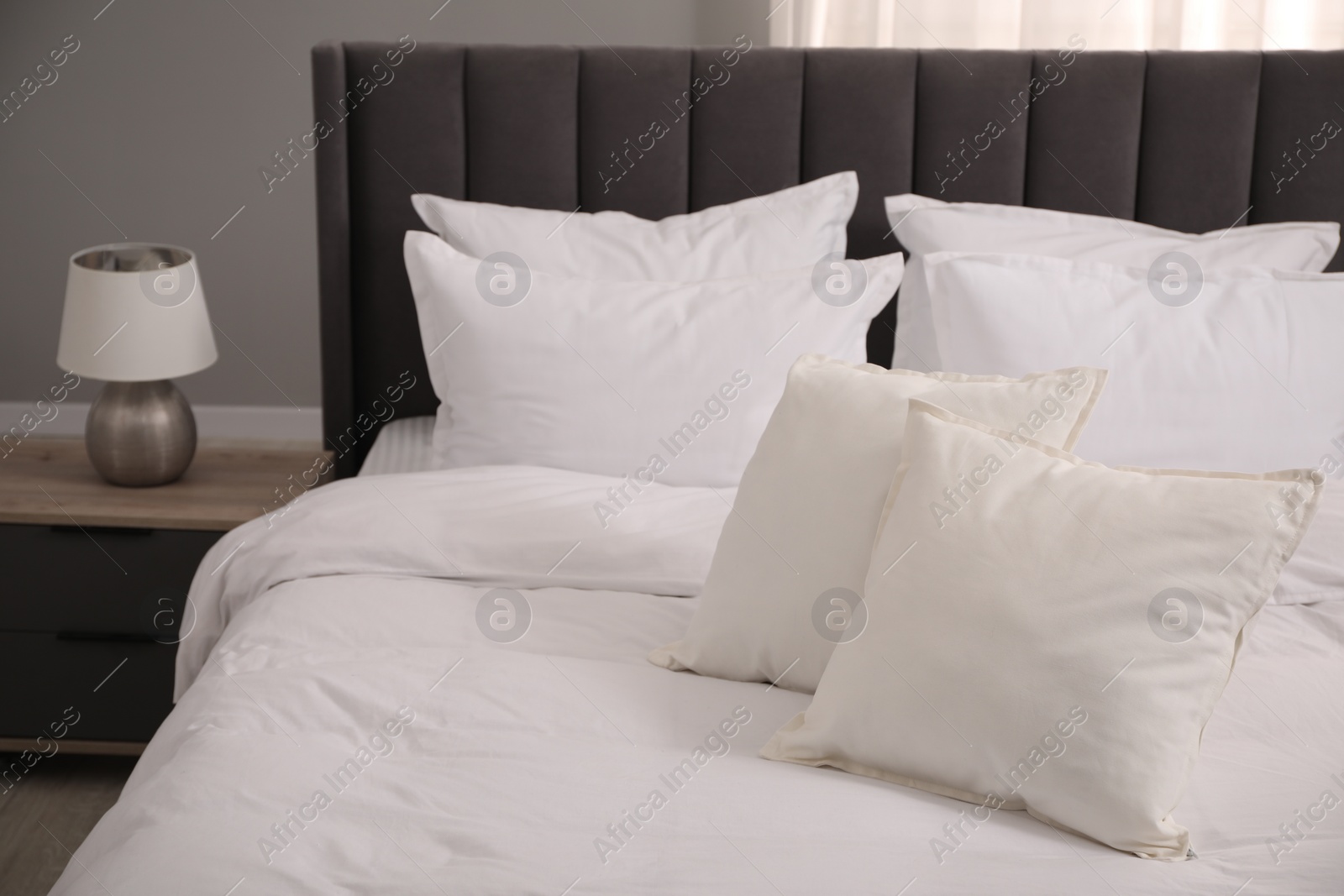 Photo of Many soft white pillows and duvet on bed indoors