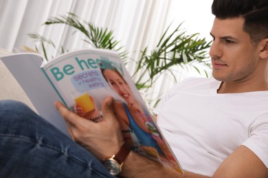 Photo of Man reading new magazine in living room, closeup