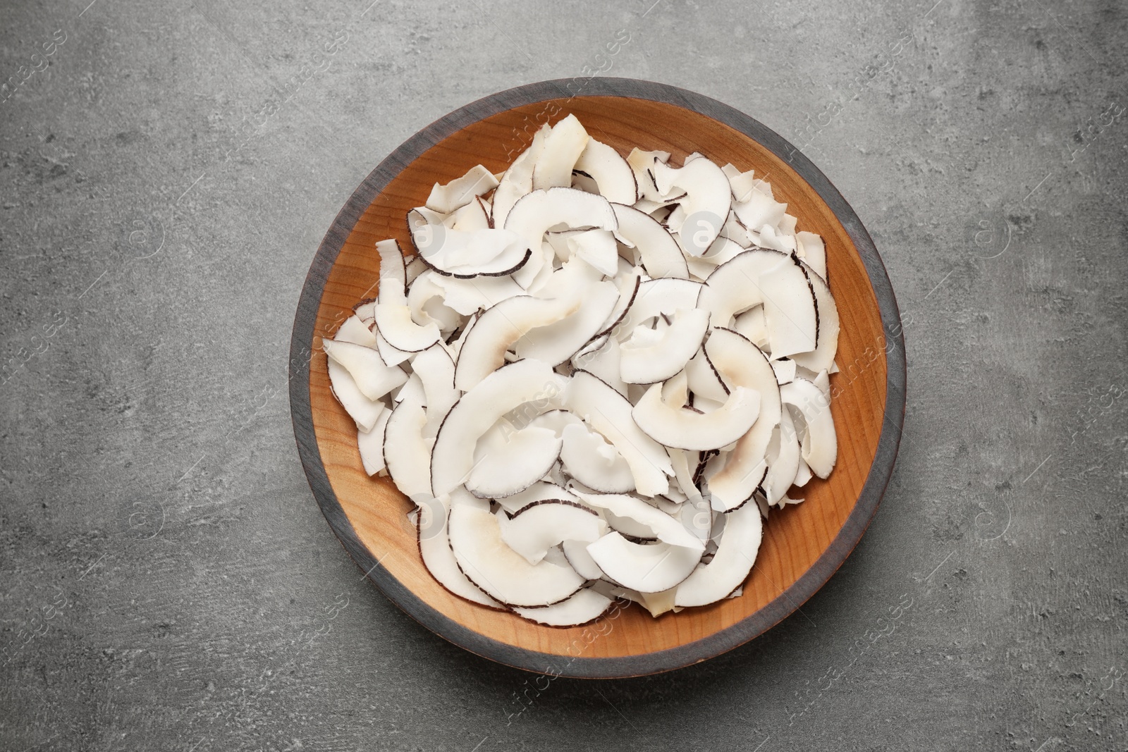 Photo of Tasty coconut chips on grey table, top view