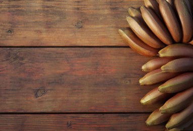 Photo of Tasty purple bananas on wooden table, top view. Space for text