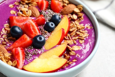 Photo of Delicious acai smoothie with granola and berries in bowl on table, closeup