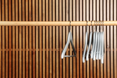 Photo of Empty hangers on rail against wooden background, space for text