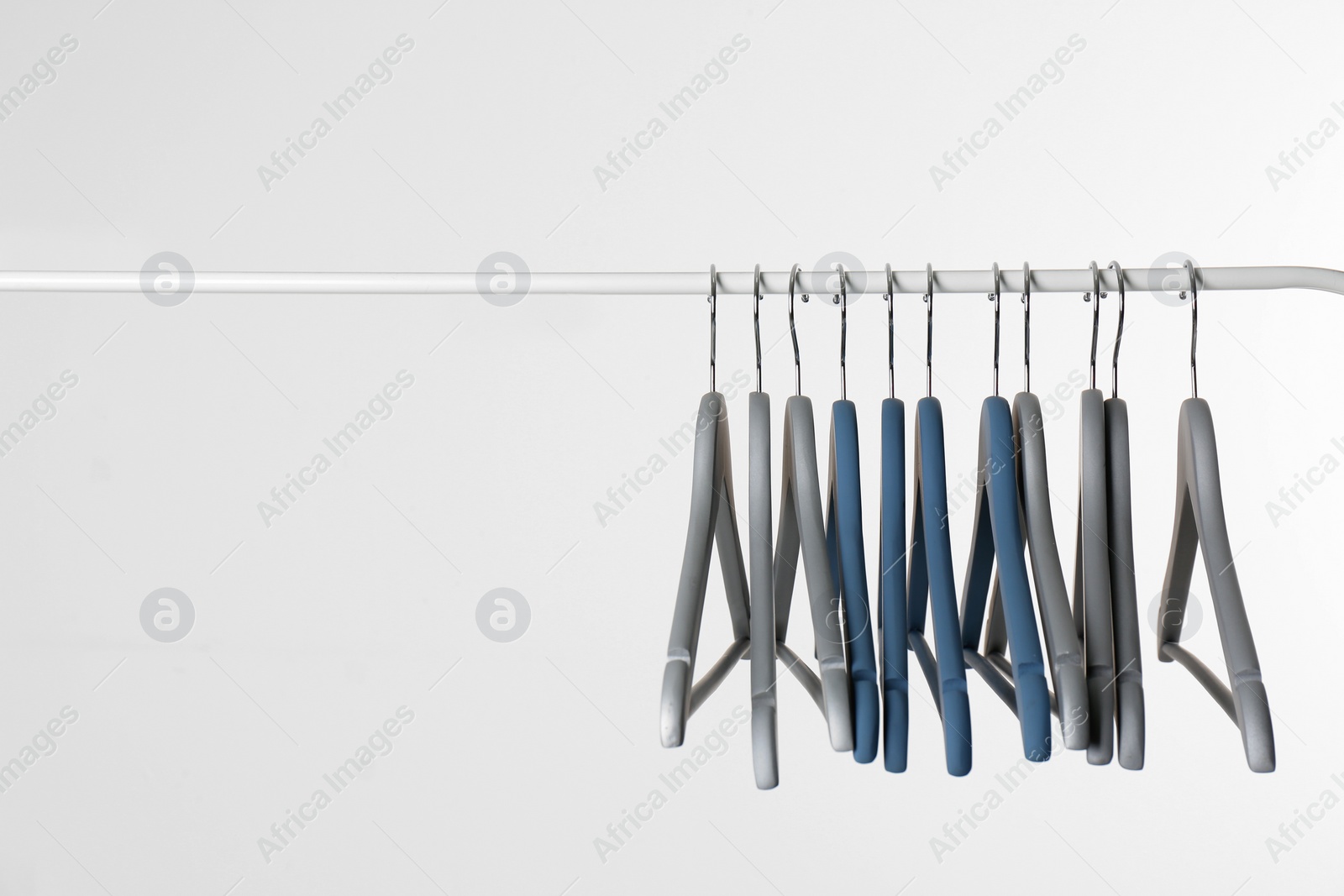 Photo of Metal rack with clothes hangers on white background, space for text